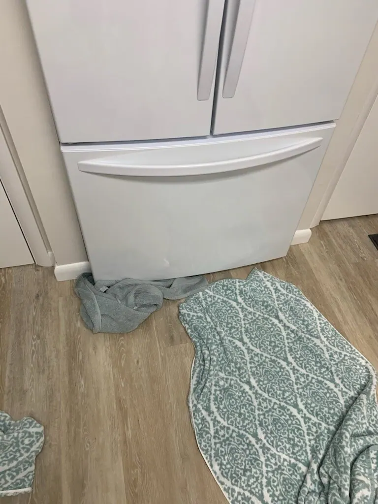 White Kenmore refrigerator in North Fort Myers with towels on the floor in front of it