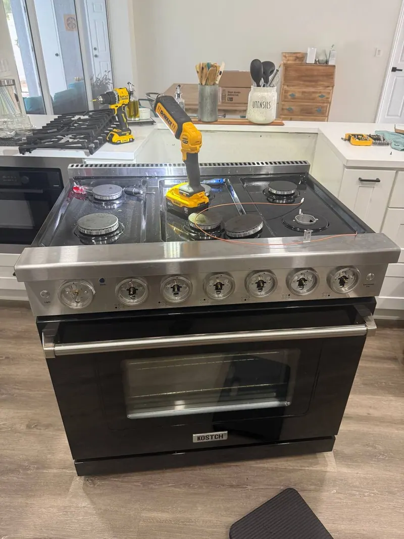 Kostch gas range with all control knobs removed and tools on the cooktop