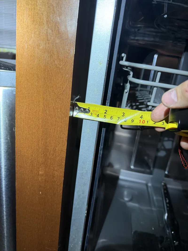 Tape measure at the gap between dishwasher and cabinet