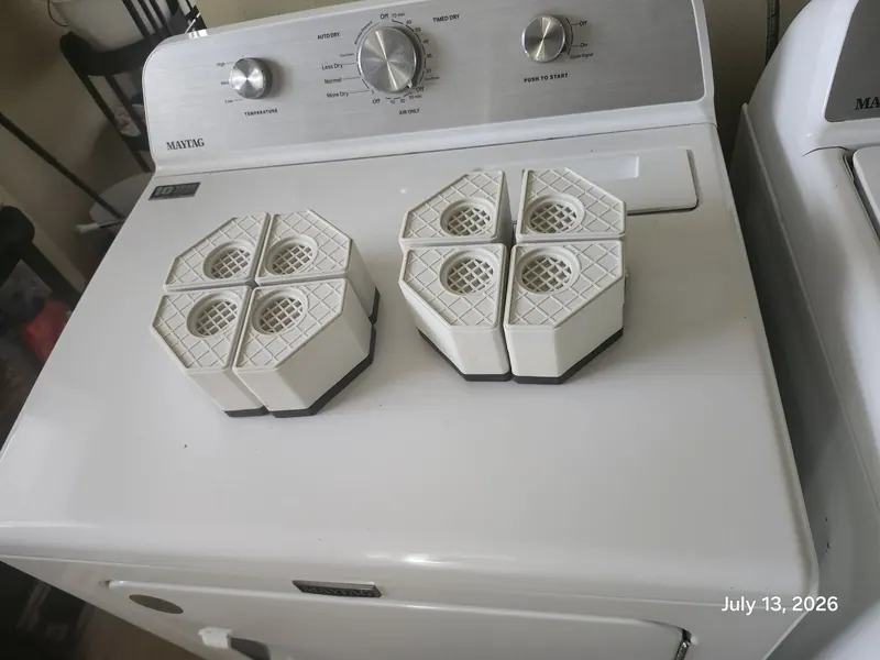 White plastic parts laid out on top of the dryer