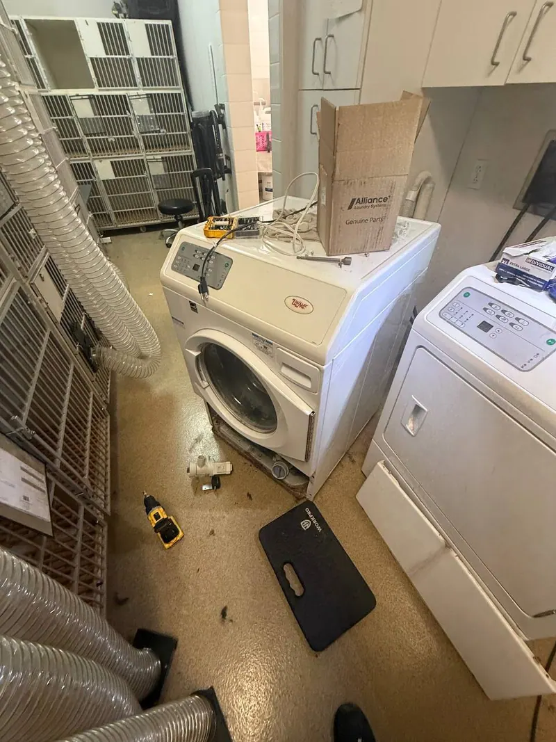 Washer under repair with tools and parts on the floor
