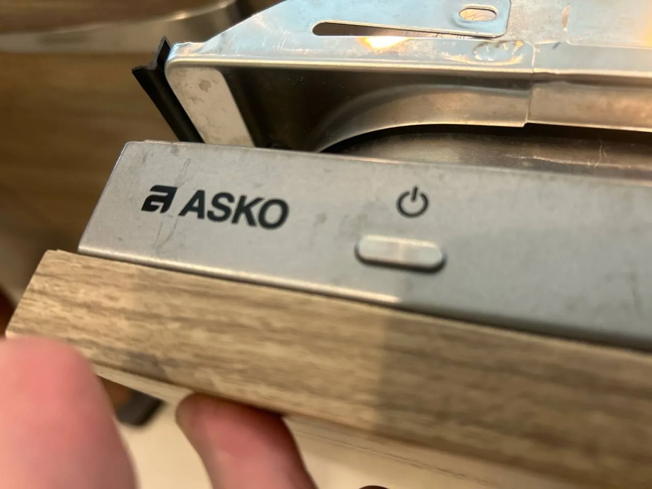 A close-up of an ASKO dishwasher's control panel and power button