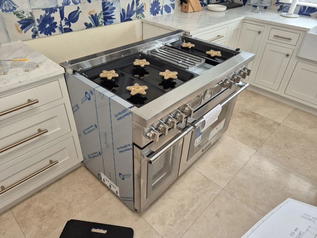 A new oven range is being installed in a kitchen with blue and white patterned backsplash tiles