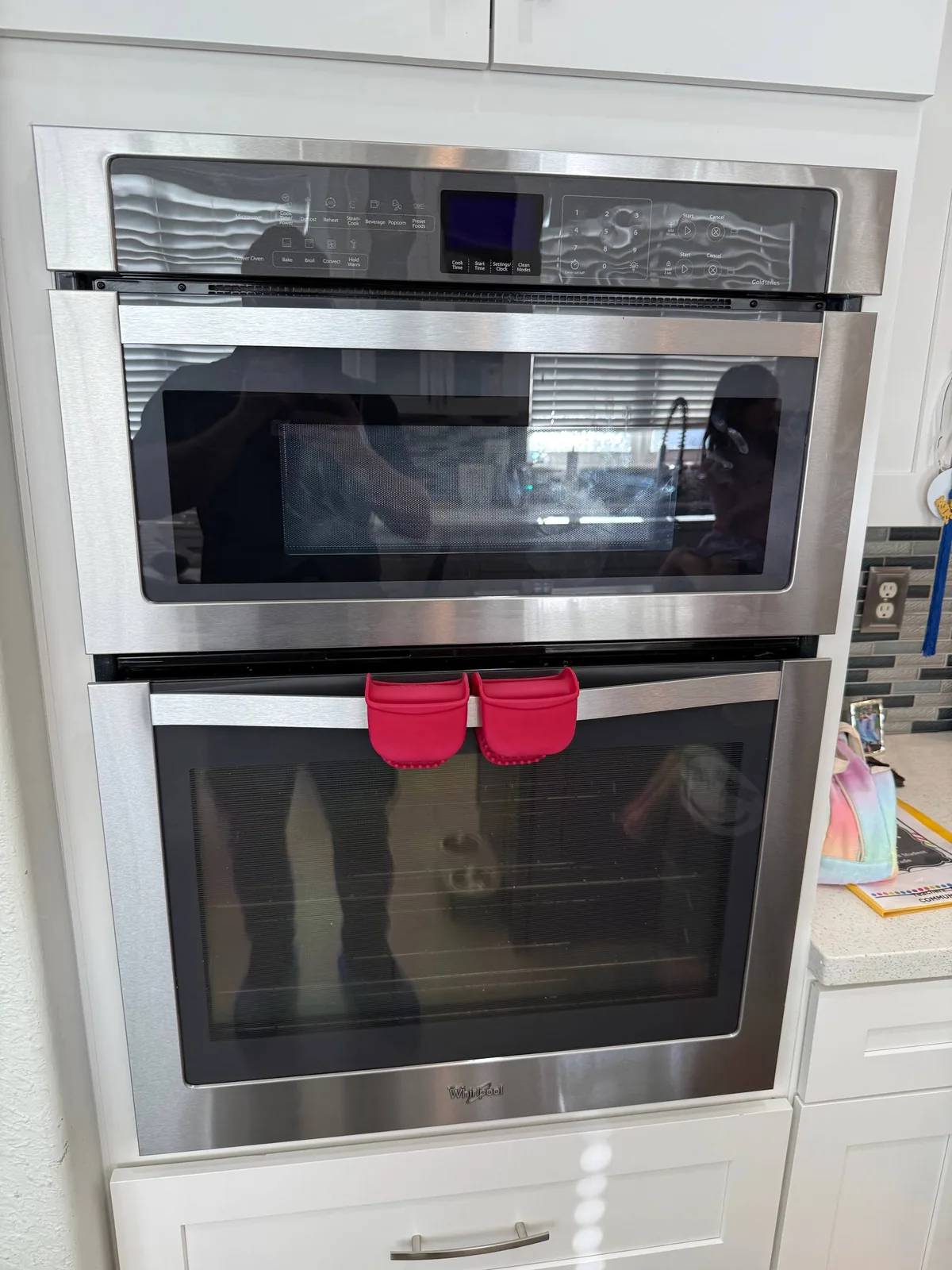 A stainless steel oven and microwave combination unit is installed in white kitchen cabinetry