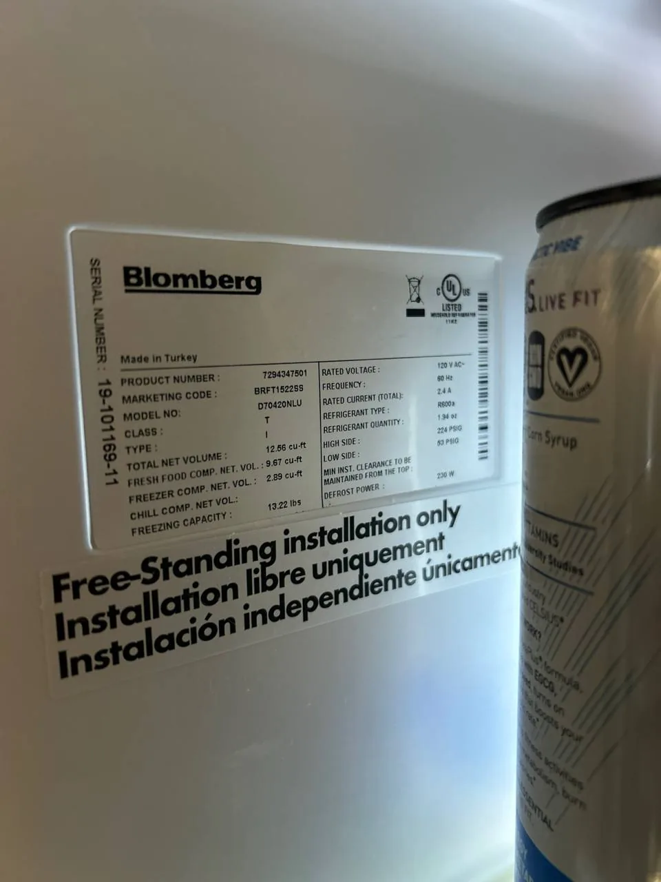A Blomberg refrigerator's rating label and installation instructions, along with a can of corn syrup