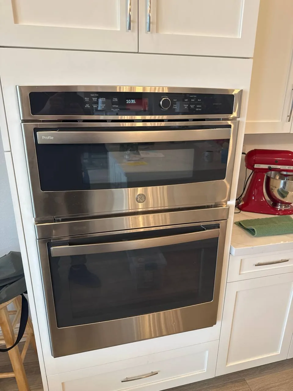 A stainless steel double oven unit is installed in white kitchen cabinetry