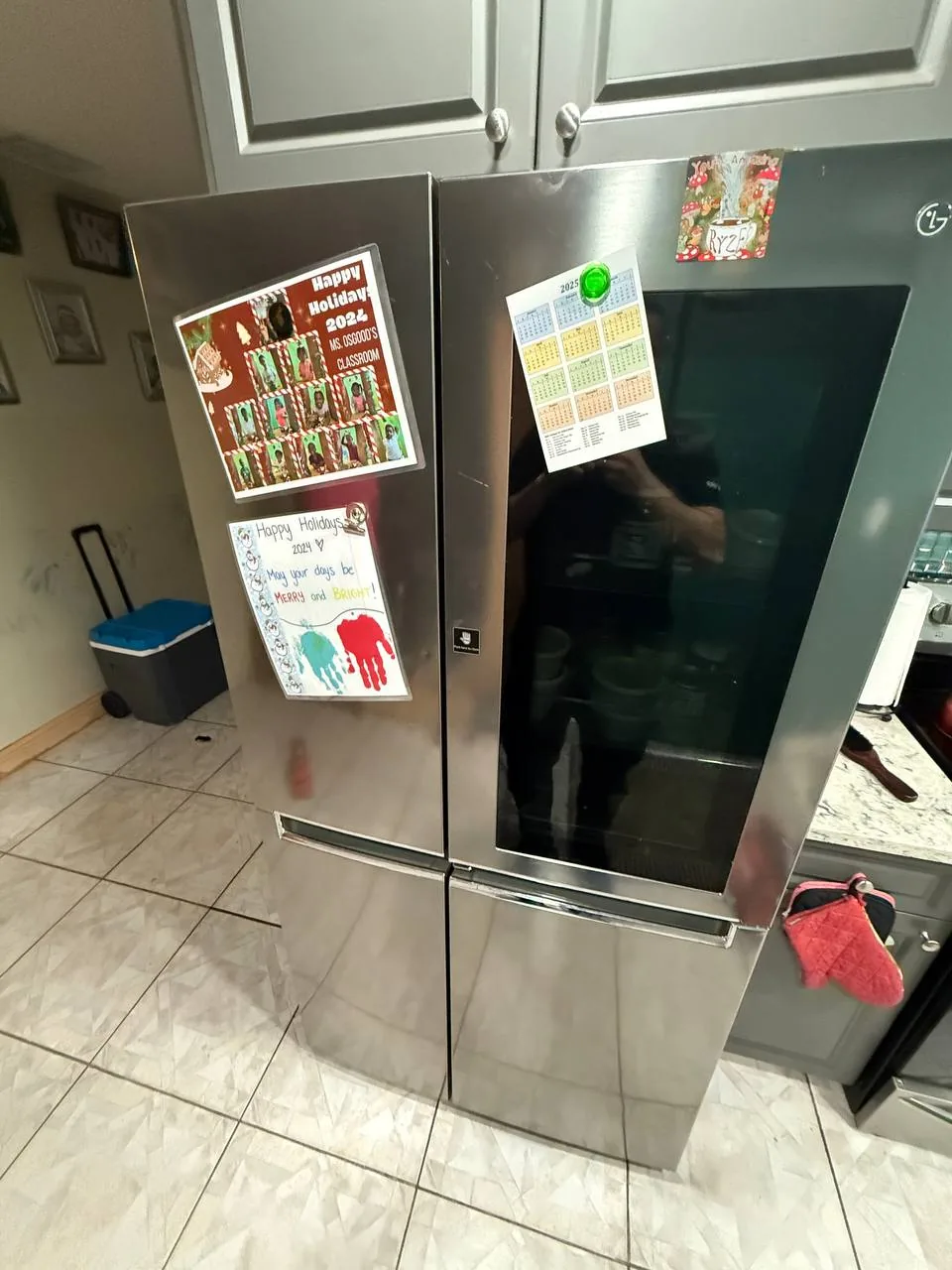 A stainless steel refrigerator with holiday decorations on it, reflecting a technician