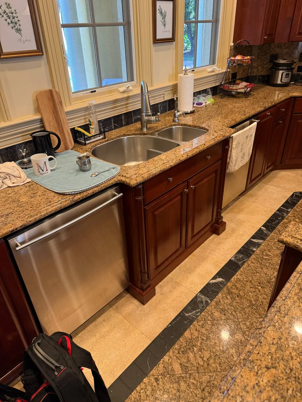 A shiny stainless steel dishwasher is installed under a granite countertop next to a kitchen sink