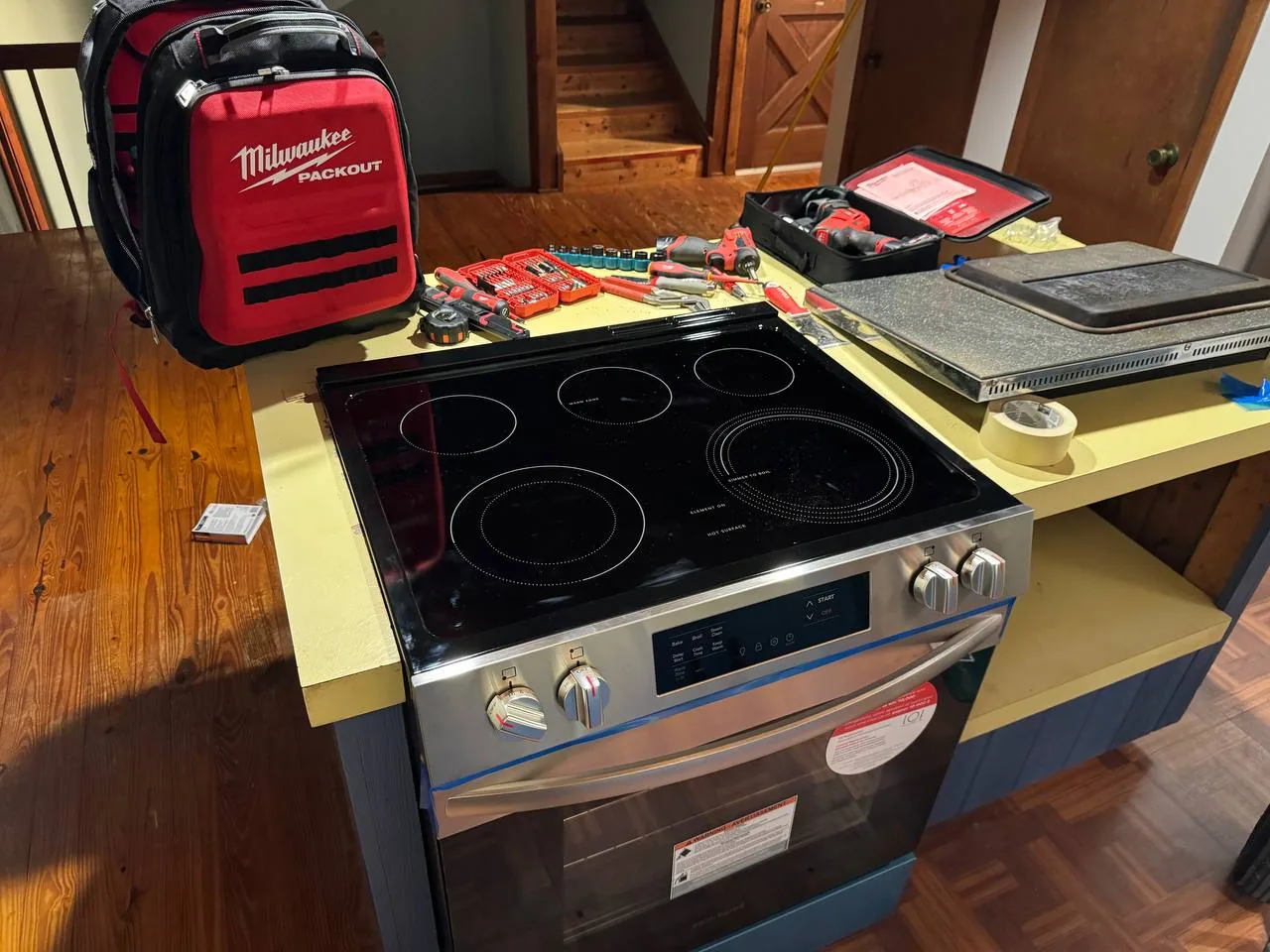 A new oven and stovetop with tools and a toolbox on a counter