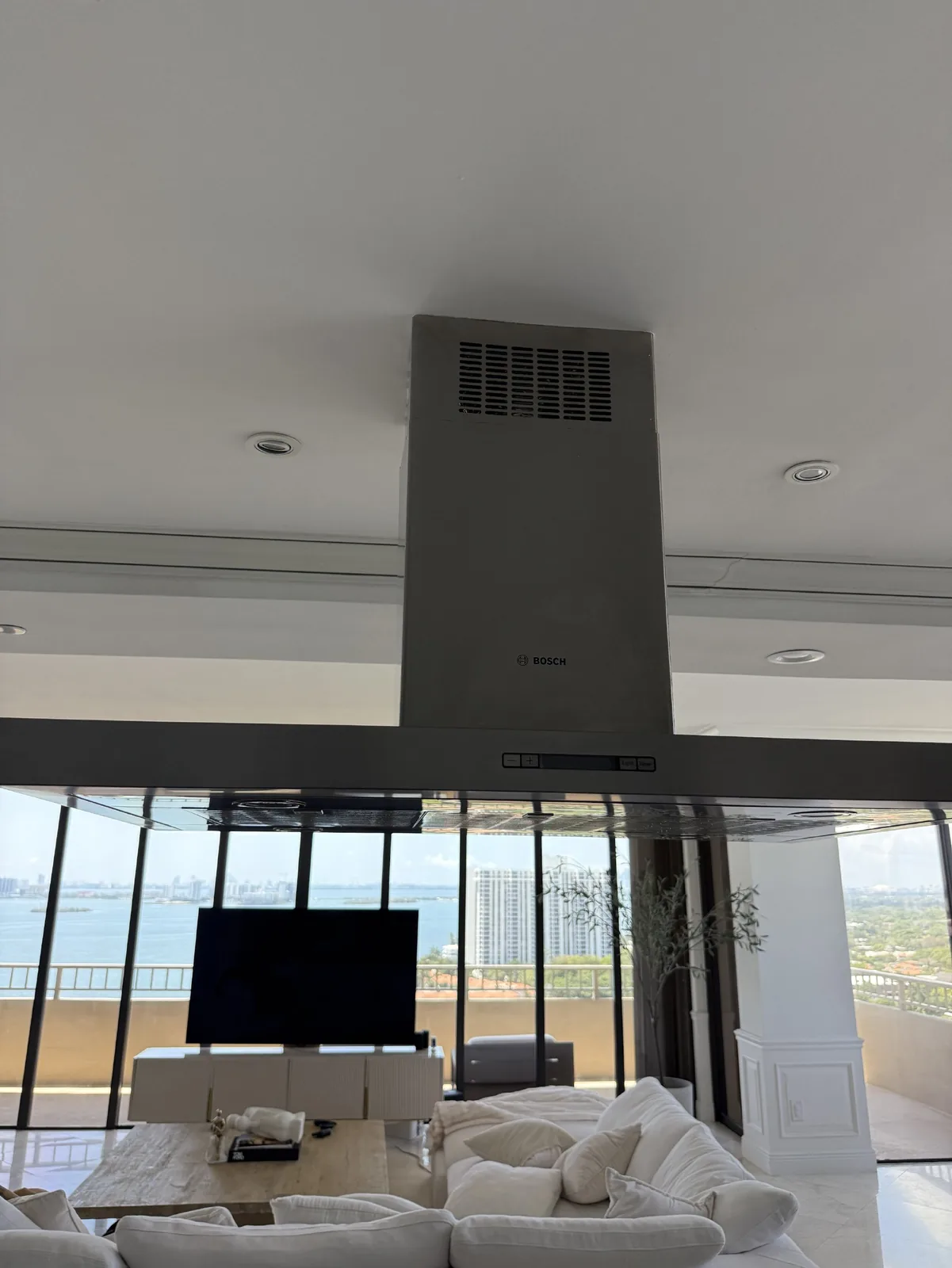 A Bosch range hood is installed in a modern kitchen overlooking a body of water and city skyline