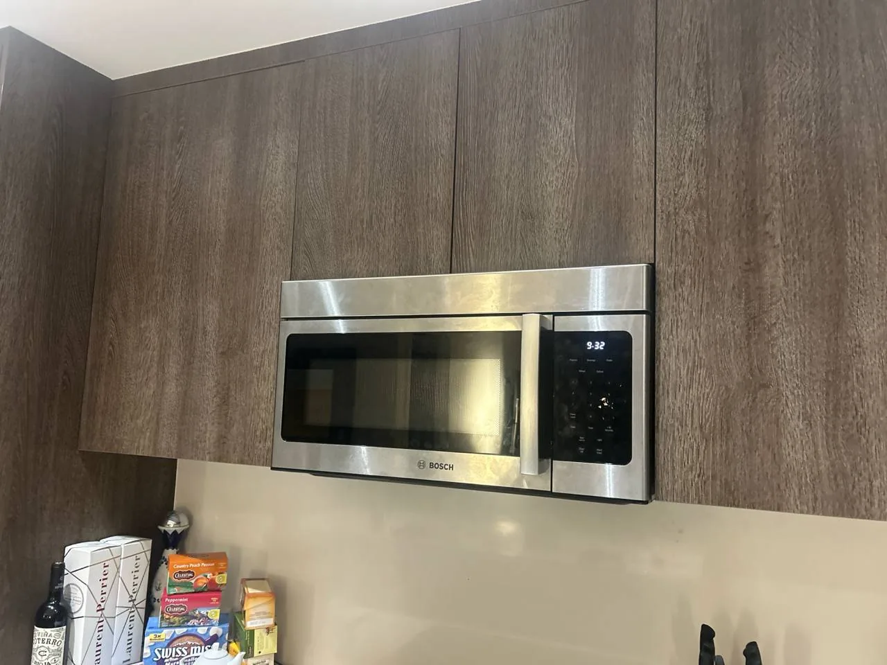 A stainless steel Bosch microwave is installed above a counter with various kitchen items