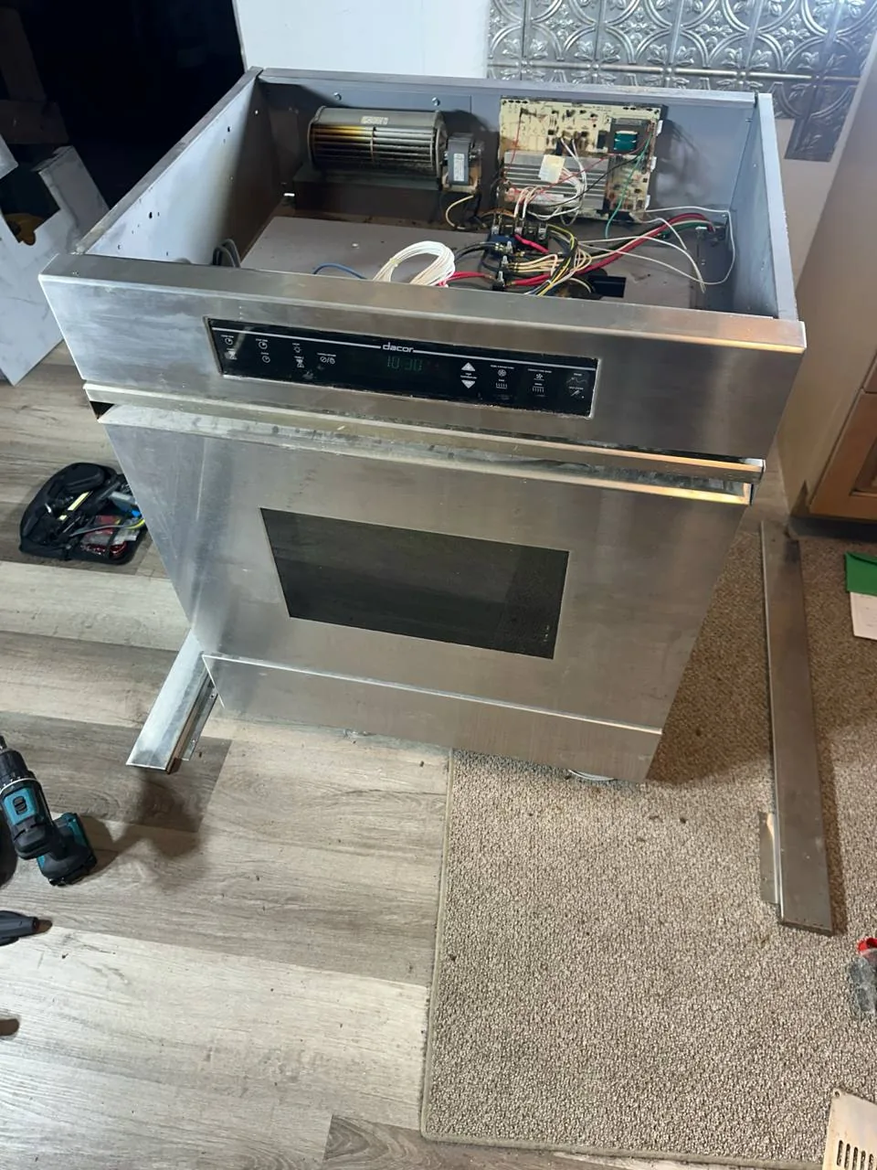 A Dacor oven with its top panel removed, revealing internal components and wiring
