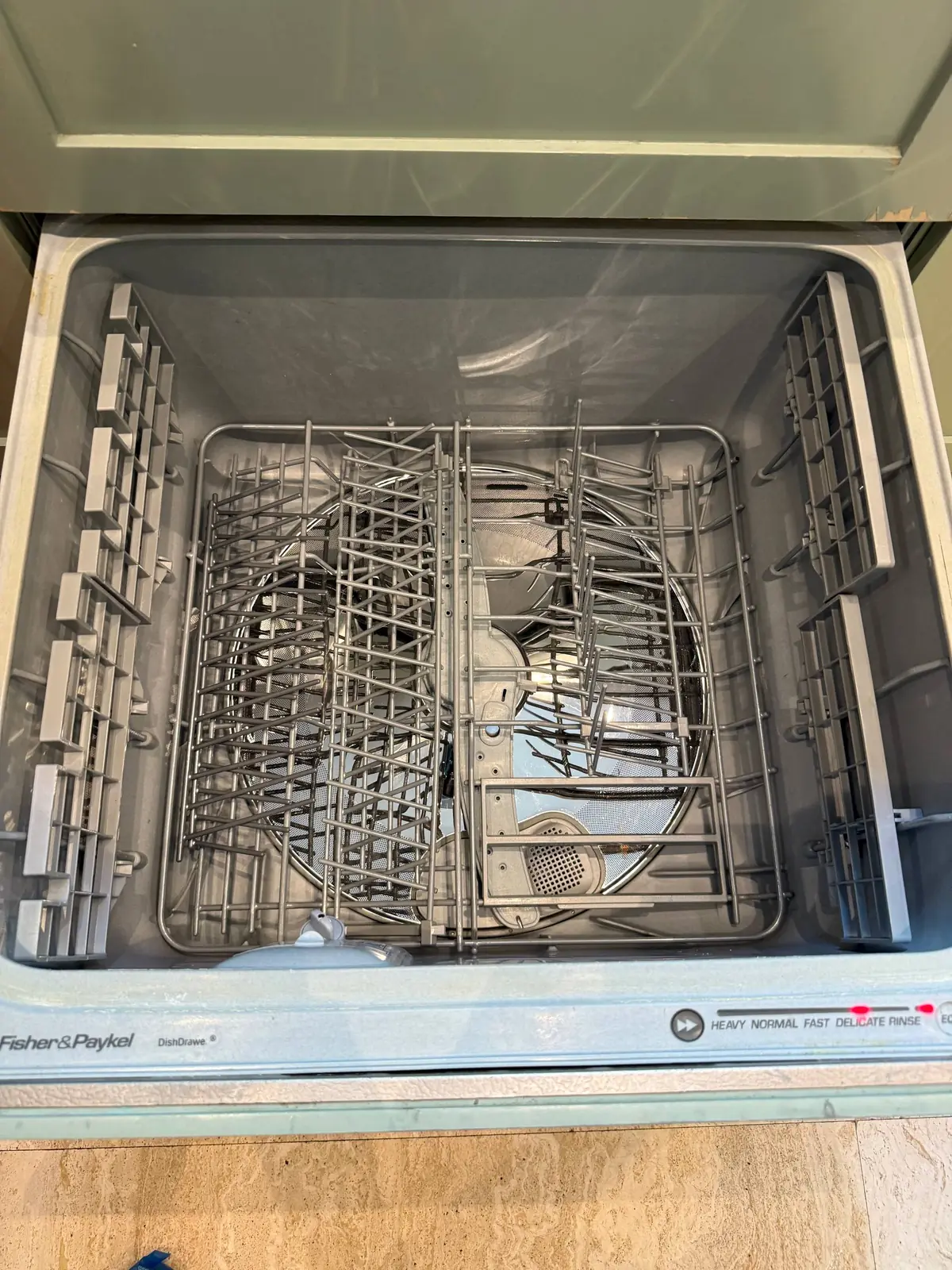 An open Fisher & Paykel DishDrawer dishwasher, with the interior racks visible and the control panel illuminated