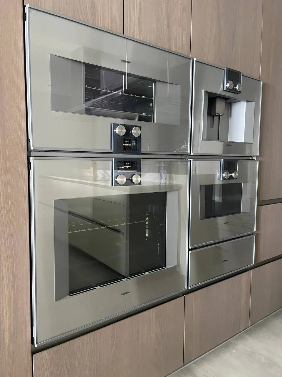 A modern kitchen features two built-in ovens and a coffee machine installed in wooden cabinetry