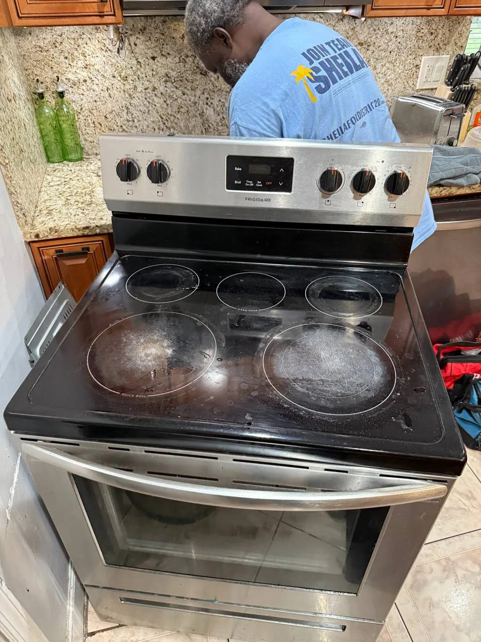 A technician is working on a Frigidaire oven in a kitchen
