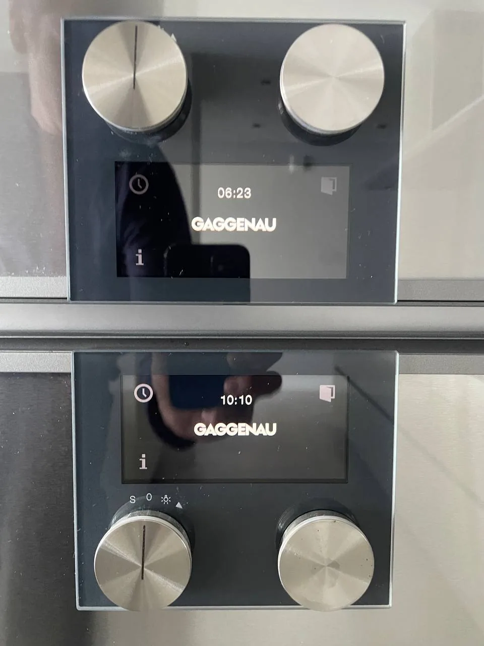 The the control panels of two stacked Gaggenau ovens, displaying the time and brand name
