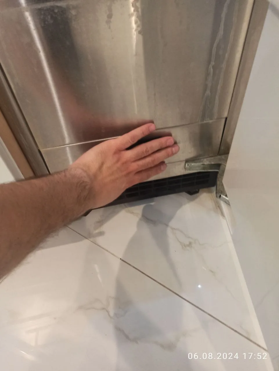A technician's hand on the stainless steel door of a refrigerator