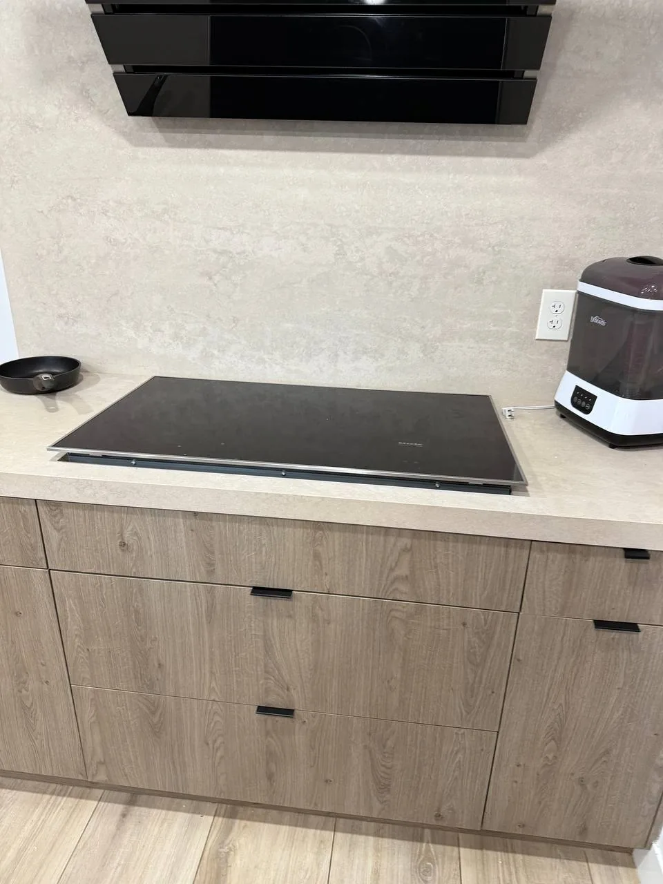 A cooktop is installed in a kitchen countertop, with a range hood above