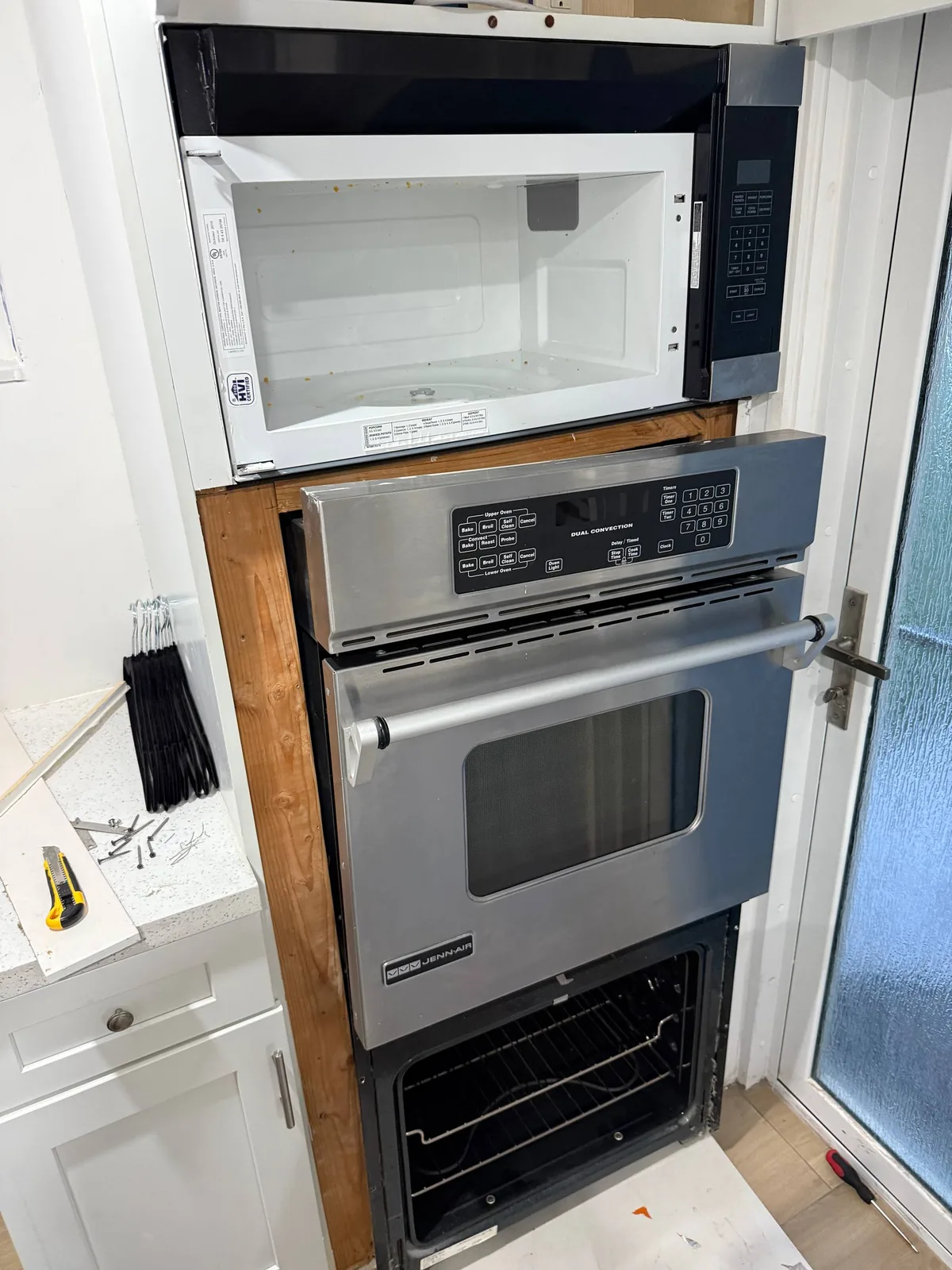 JennAir oven service: a Jenn-Air microwave and oven unit in a kitchen, with the oven door open and various tools on the