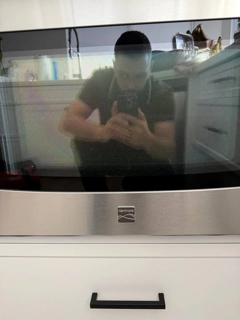 A technician is reflected in the glass of a Kenmore oven