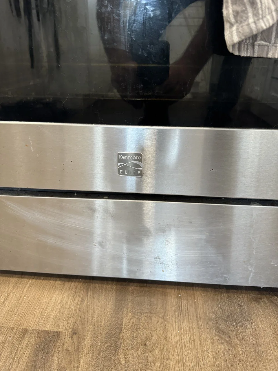 A Kenmore Elite oven with a technician's reflection visible in the glass