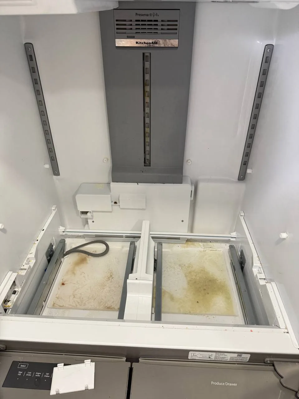 An the inside of a KitchenAid refrigerator, with components removed to reveal dirty surfaces