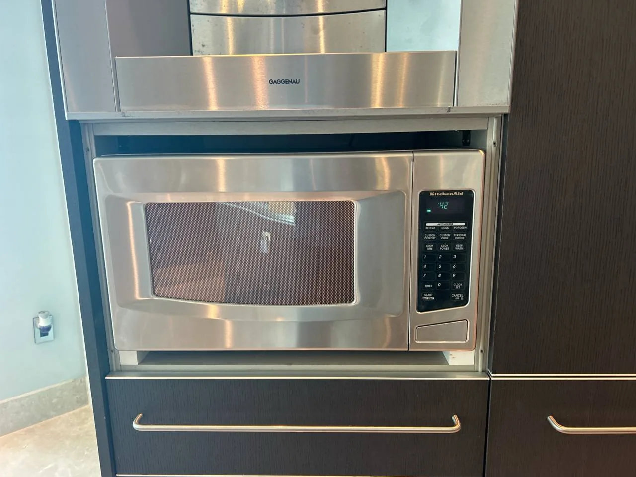 A stainless steel KitchenAid microwave is installed above a dark wood cabinet