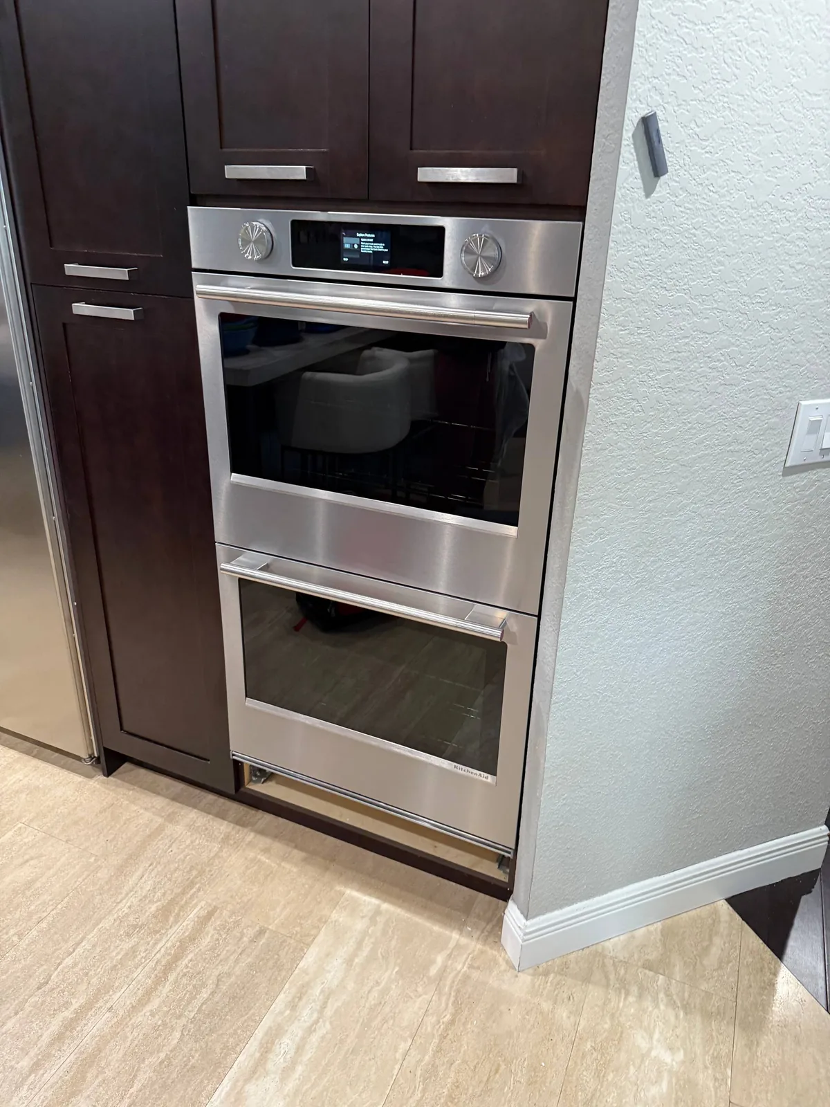 A stainless steel double oven is installed in dark wood cabinetry