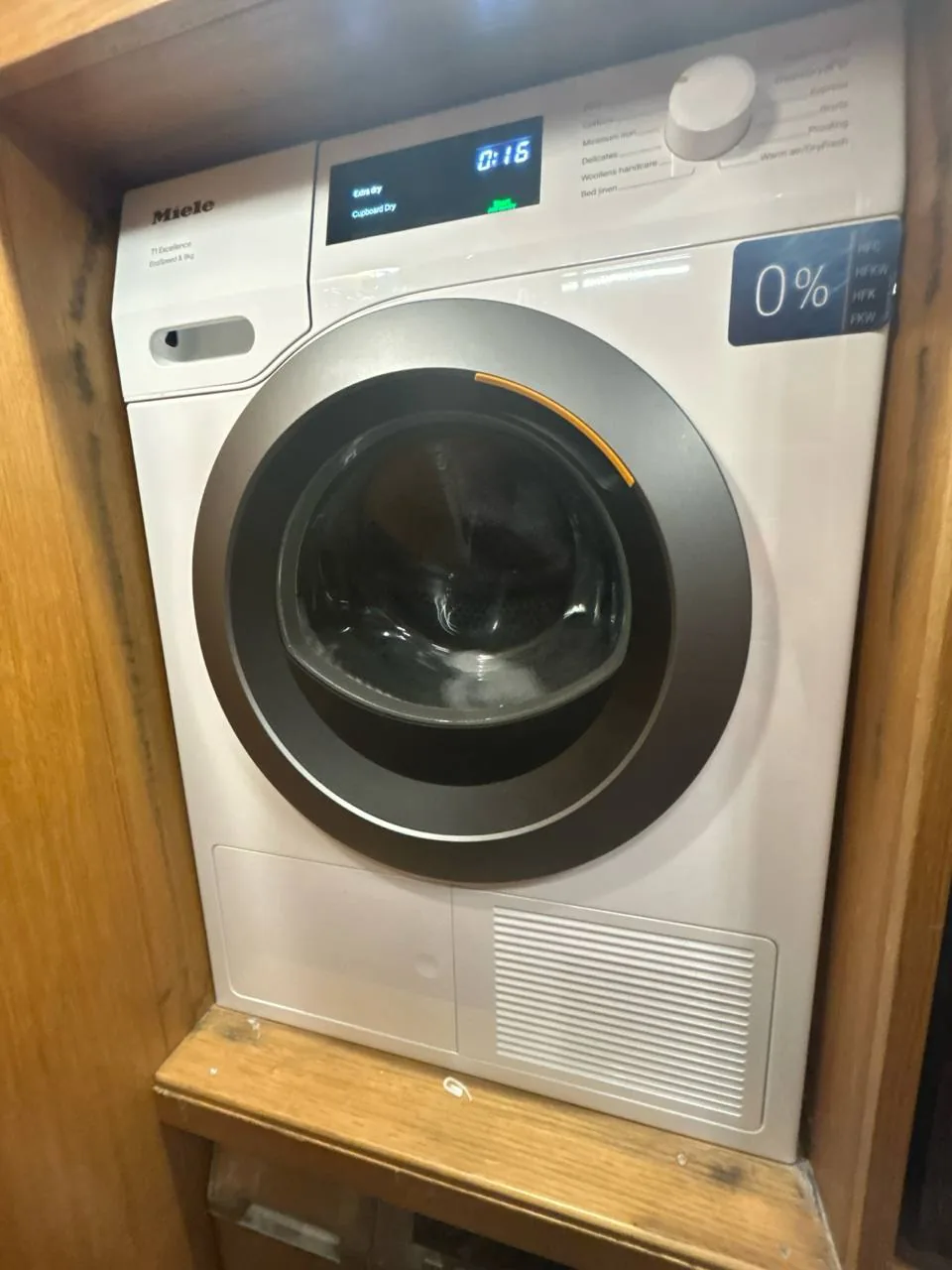 A Miele dryer installed in a wooden cabinet