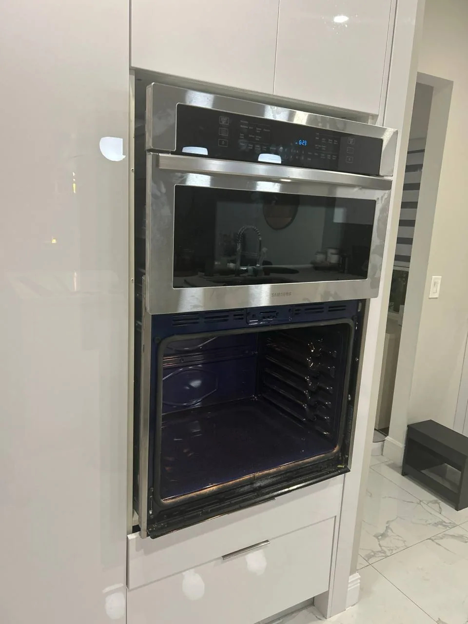A stainless steel Samsung oven and microwave combination unit installed in kitchen cabinetry, with the oven door open
