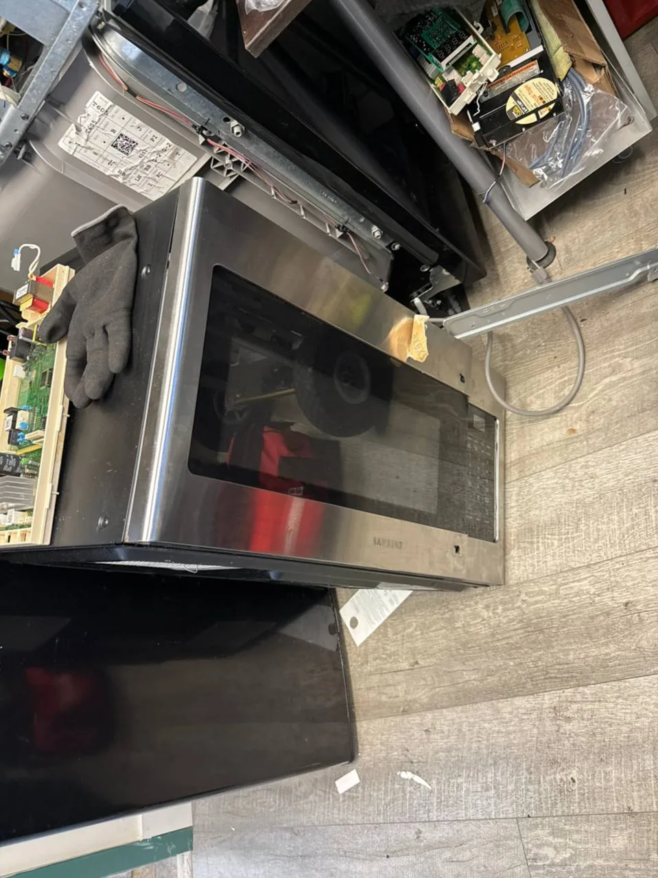 A stainless steel Samsung microwave with its internal components exposed during a repair