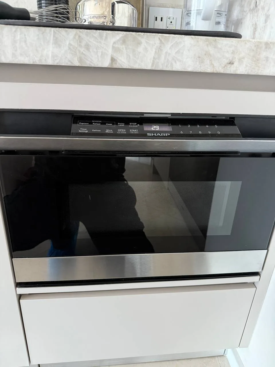 A Sharp microwave, built into a kitchen cabinet