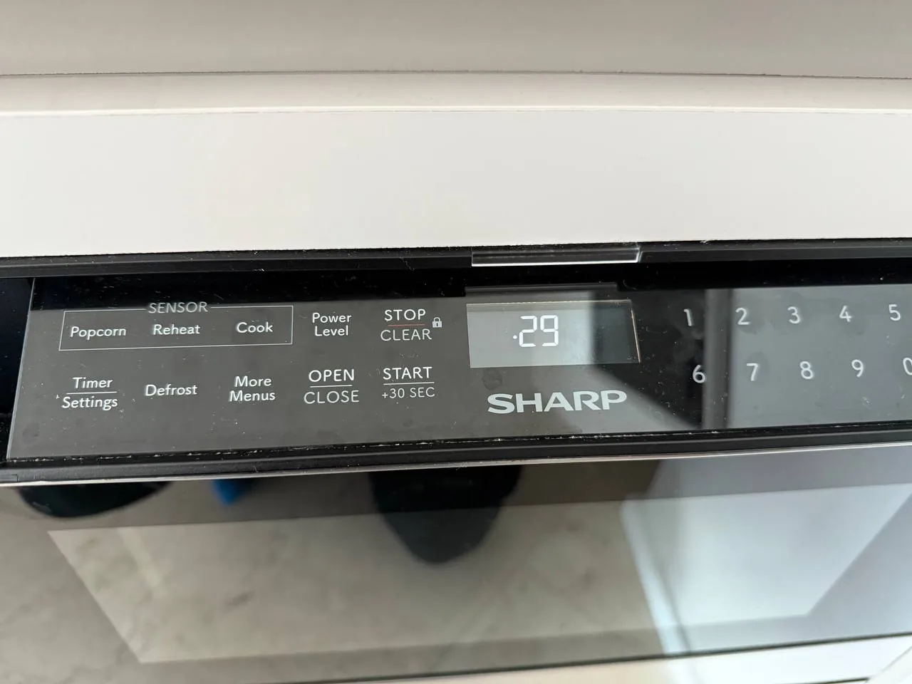 A close-up of a Sharp microwave control panel with a digital display showing ".29"