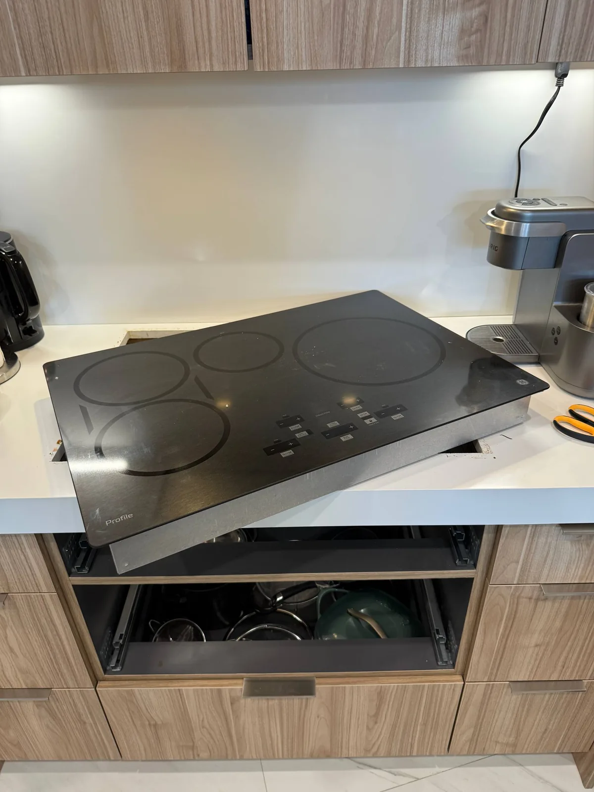 A cooktop is being repaired on a kitchen counter