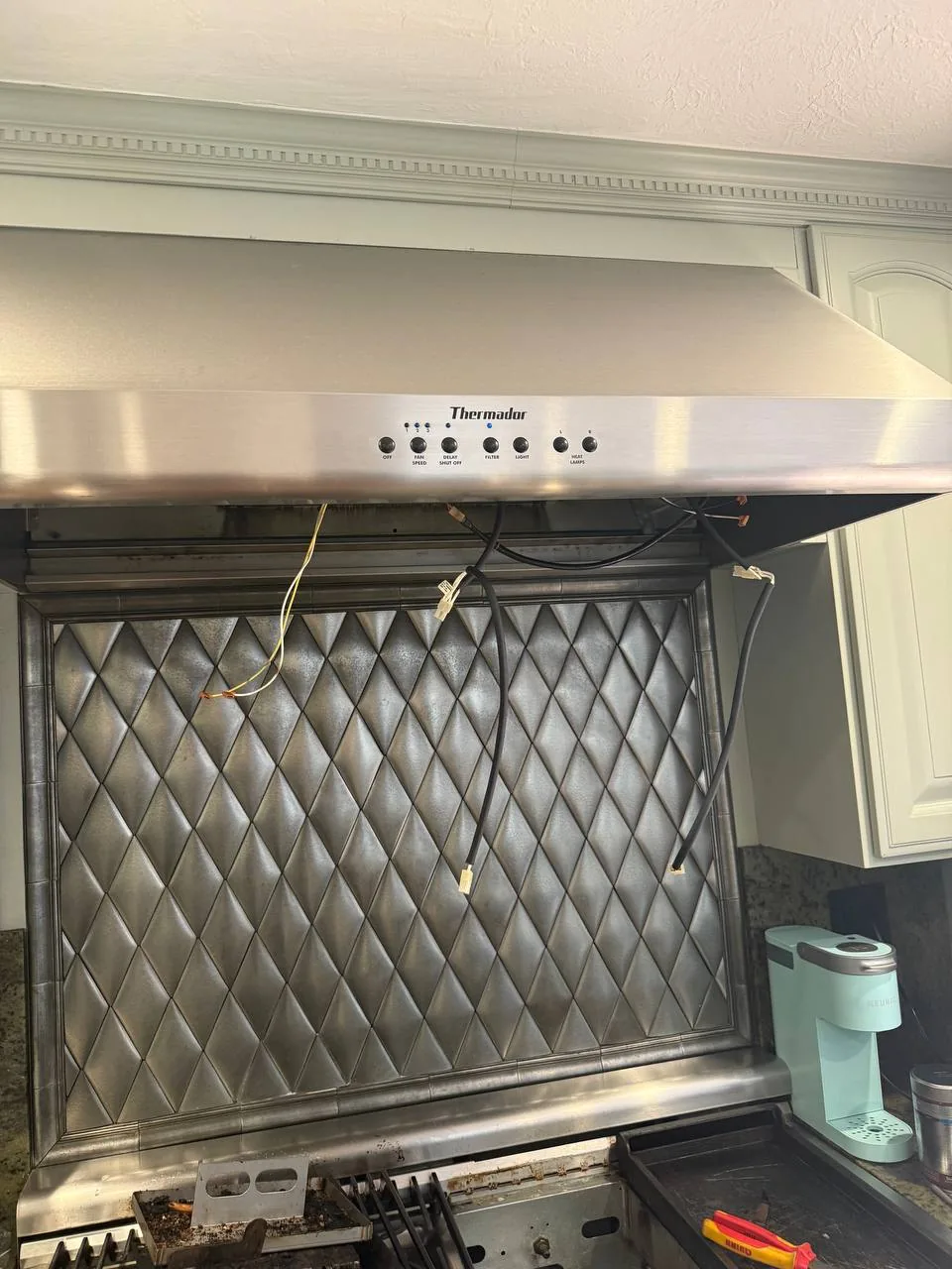 A Thermador range hood with exposed wiring during a repair