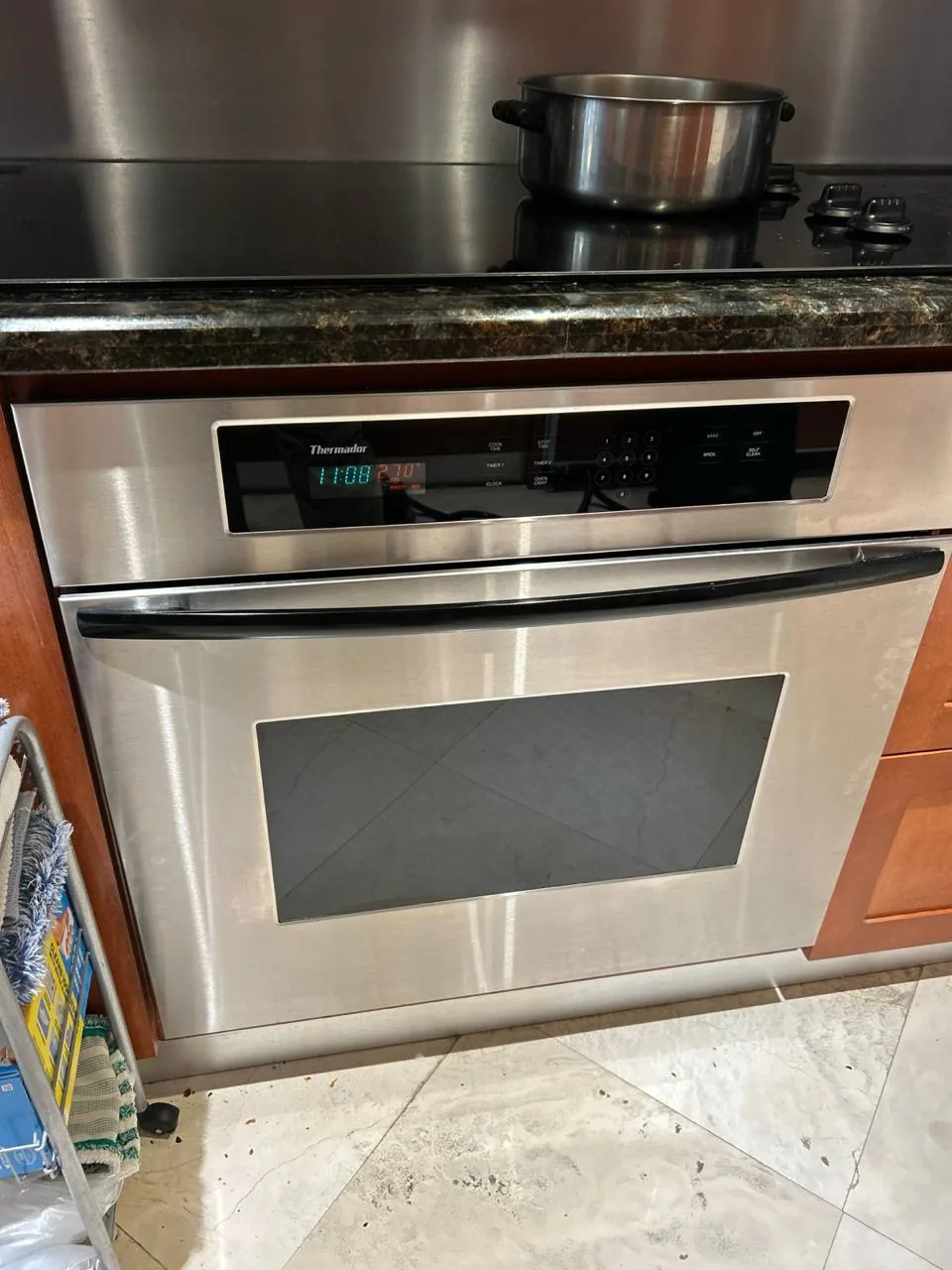 A stainless steel Thermador wall oven below a black cooktop with a pot