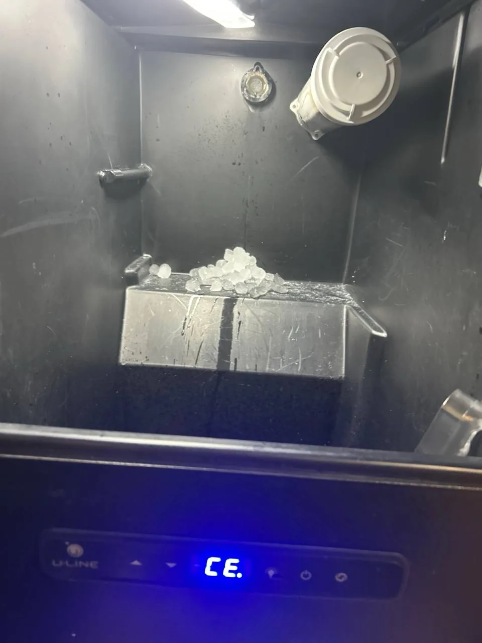 A U-Line ice maker displays an error code 'CE' with some ice present in the bin
