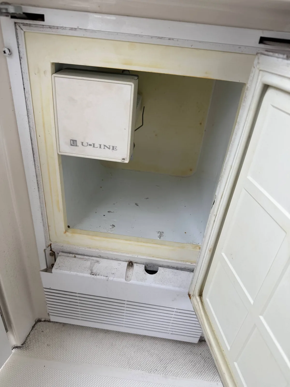 A U-Line brand refrigerator with its door open, revealing the interior of the appliance
