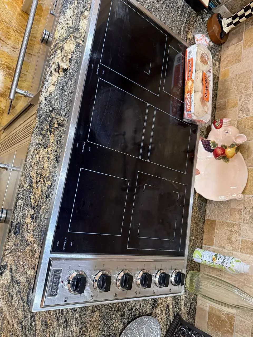 A Viking brand cooktop with a package of bread and decorative items on the granite countertop