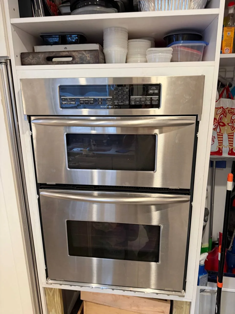 A stainless steel double oven installed in a white kitchen cabinet