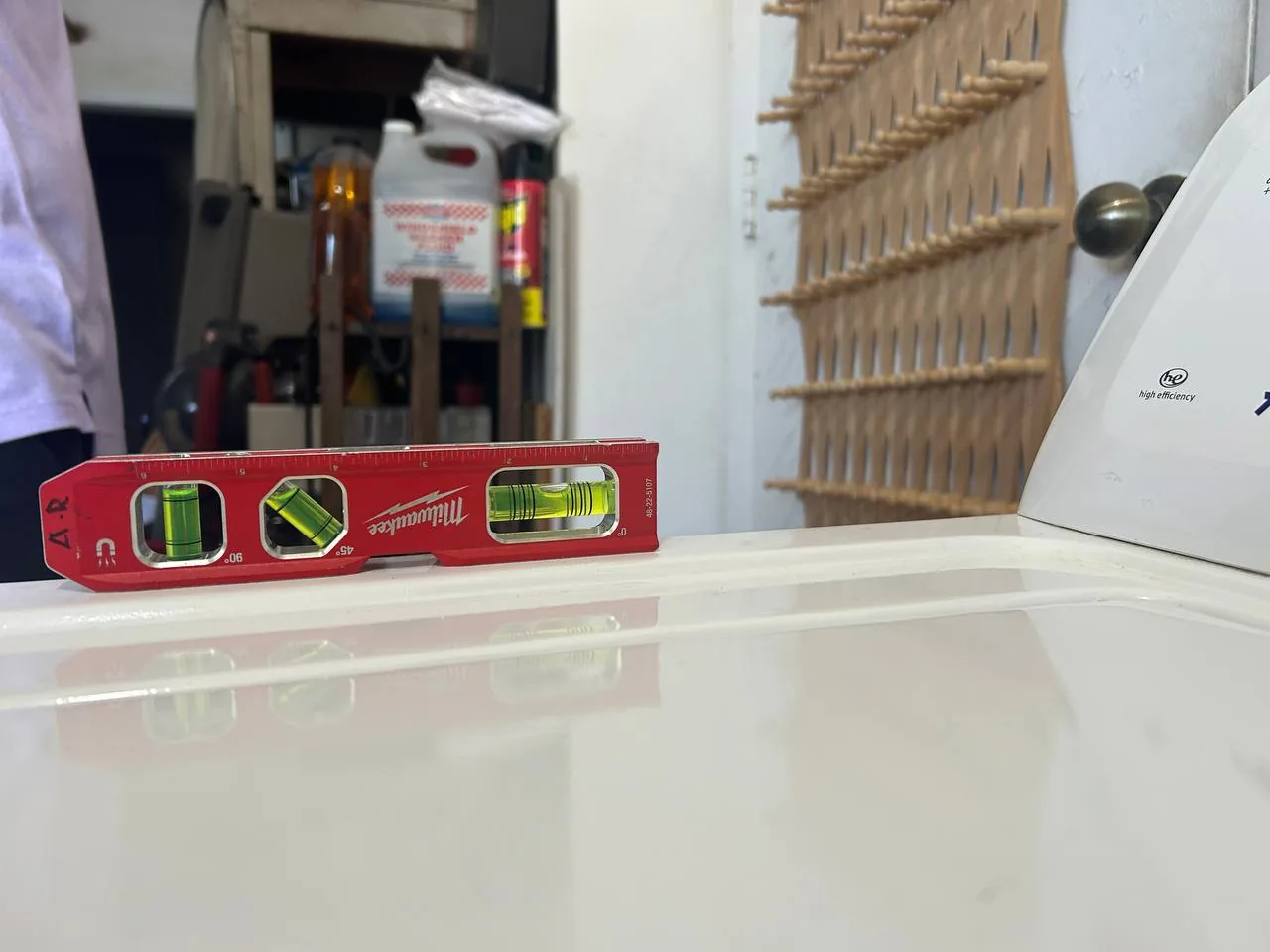 A level tool is placed on top of a white washer, with a technician partially visible in the background