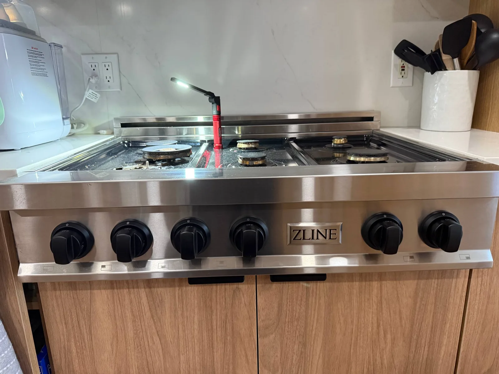 A ZLINE cooktop with a red flashlight illuminating the burners