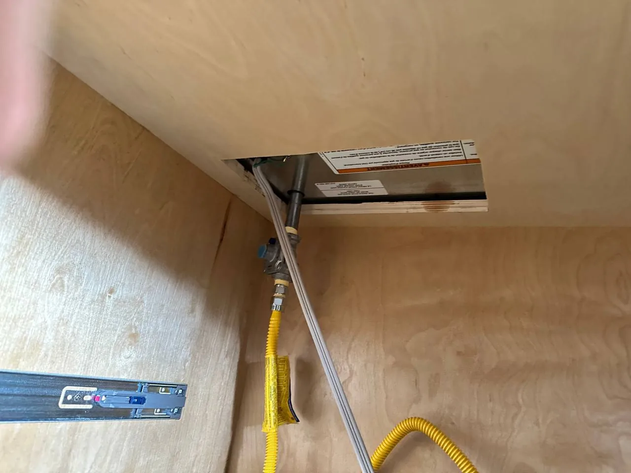 This the gas and electrical connections for a cooktop installation under a wooden counter